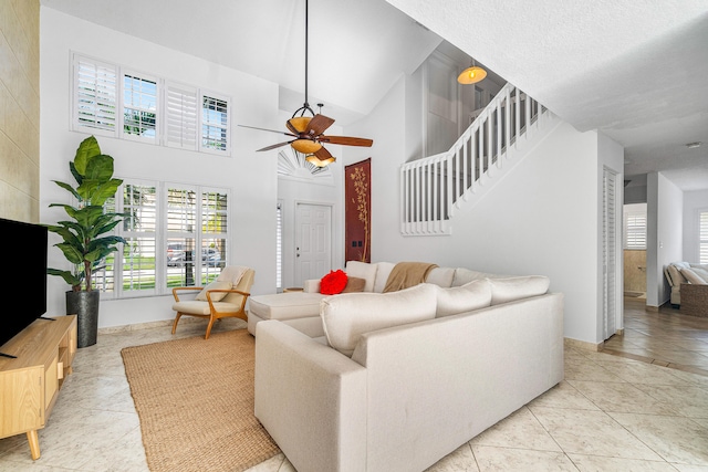 tiled living room with ceiling fan and a towering ceiling