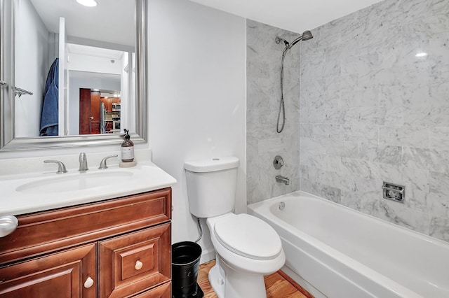 full bathroom with tiled shower / bath, hardwood / wood-style flooring, vanity, and toilet