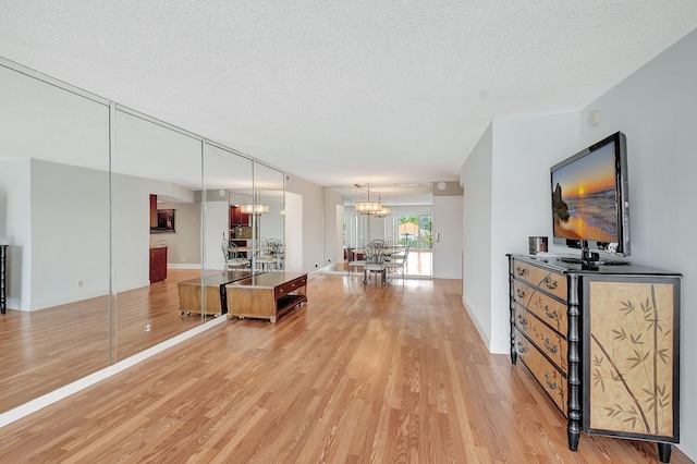 interior space with a textured ceiling, light hardwood / wood-style floors, and an inviting chandelier