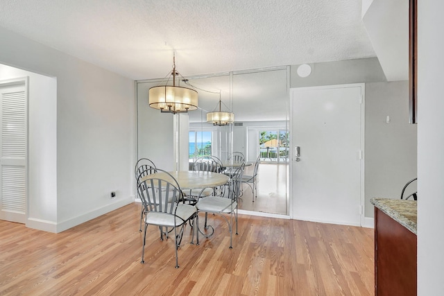 dining room featuring an inviting chandelier, a textured ceiling, and light hardwood / wood-style floors