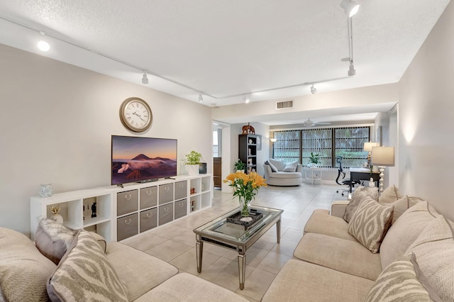 living room with track lighting, ceiling fan, light tile patterned flooring, and a textured ceiling