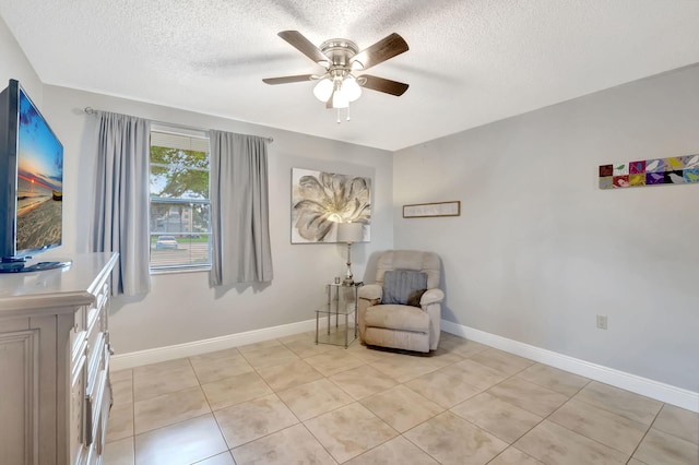 living area featuring a textured ceiling, light tile patterned floors, and ceiling fan