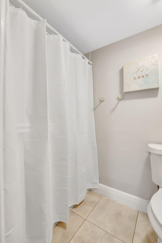 bathroom featuring tile patterned flooring, toilet, and walk in shower