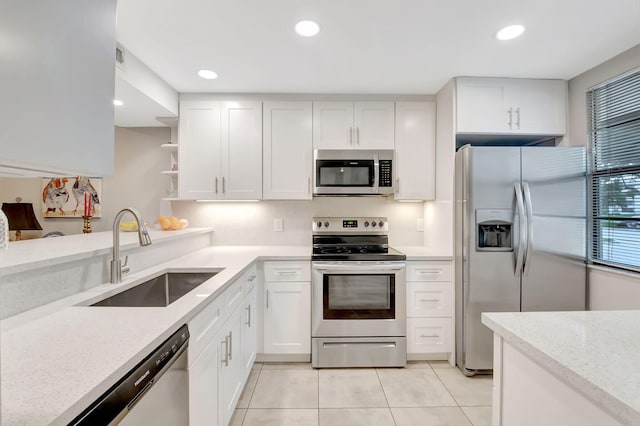 kitchen featuring appliances with stainless steel finishes, light stone counters, white cabinetry, and sink