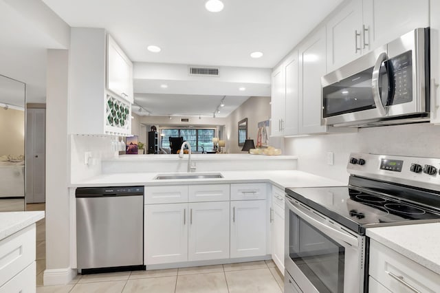 kitchen featuring sink, light tile patterned floors, appliances with stainless steel finishes, and white cabinets