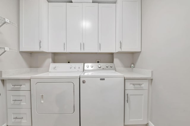 clothes washing area with cabinets and separate washer and dryer