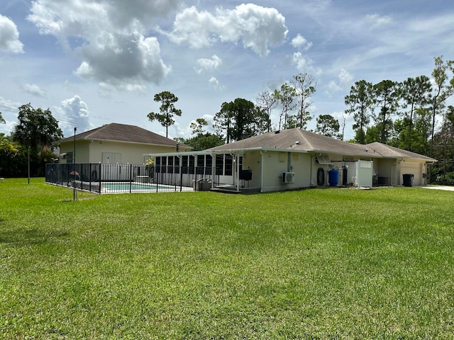 back of property with a fenced in pool and a lawn