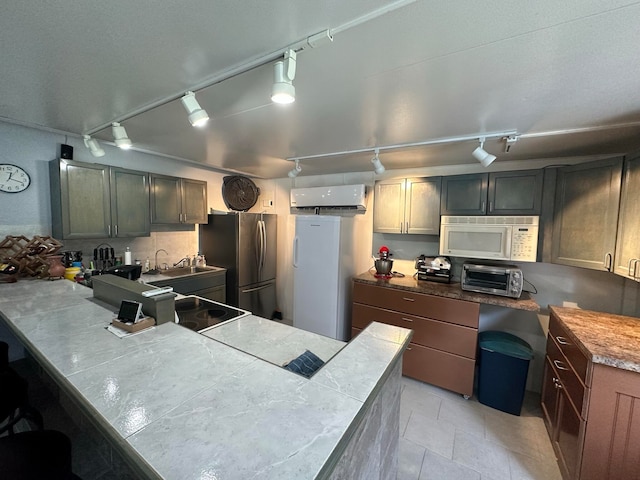 kitchen featuring stainless steel refrigerator, rail lighting, fridge, light tile patterned floors, and sink