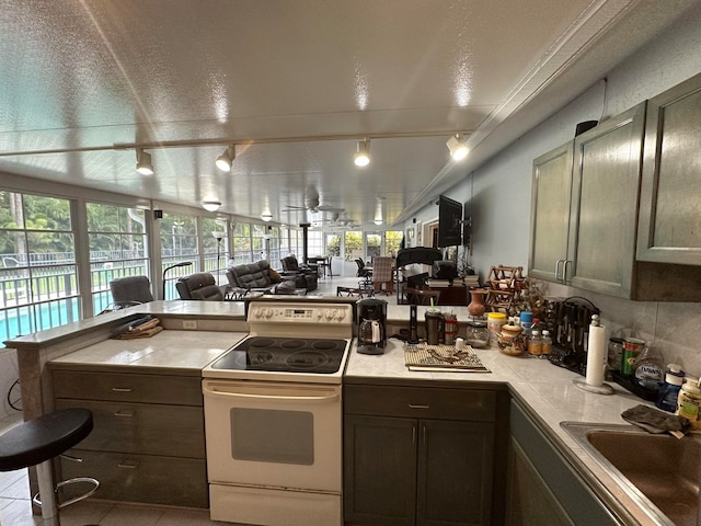 kitchen featuring a textured ceiling, rail lighting, electric stove, and tile patterned floors