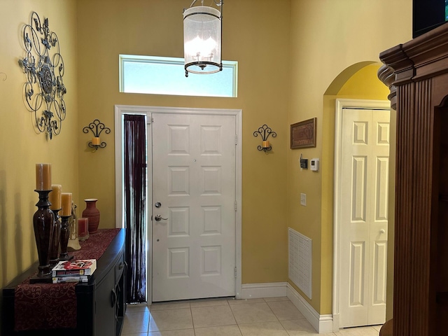 tiled foyer entrance featuring a chandelier and a high ceiling