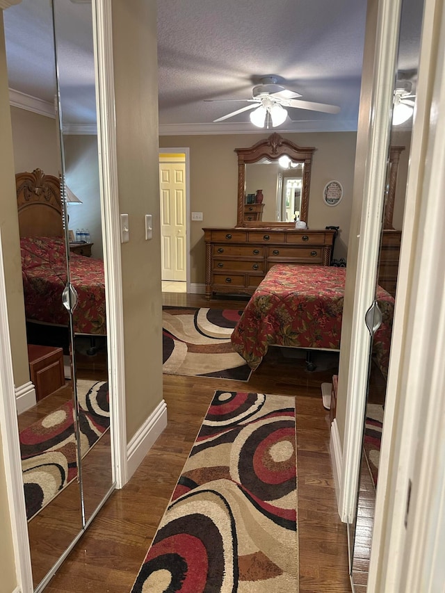 bedroom with ornamental molding, ceiling fan, dark hardwood / wood-style floors, and a textured ceiling