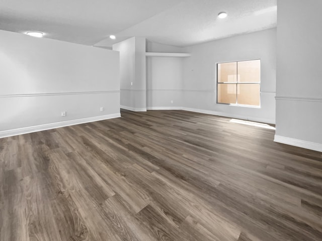 empty room featuring baseboards and dark wood-style flooring