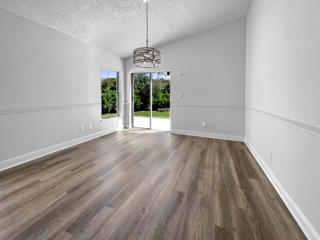 spare room with a textured ceiling, dark hardwood / wood-style flooring, and a notable chandelier