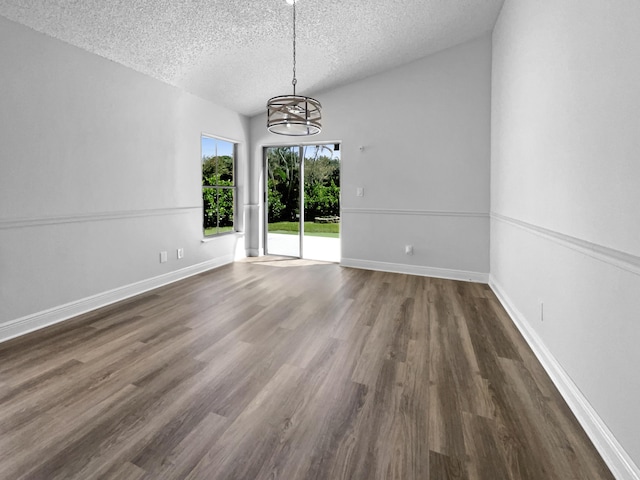 unfurnished dining area featuring an inviting chandelier, wood finished floors, baseboards, and a textured ceiling