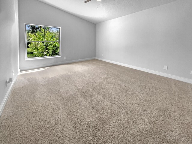 spare room featuring vaulted ceiling, a textured ceiling, ceiling fan, and carpet floors