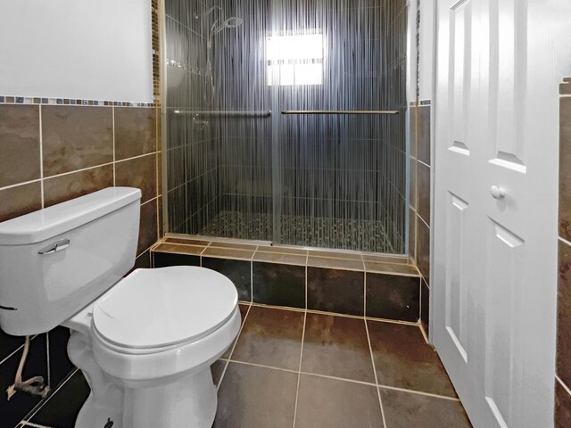 bathroom featuring tile walls, toilet, tile patterned flooring, and a shower with door