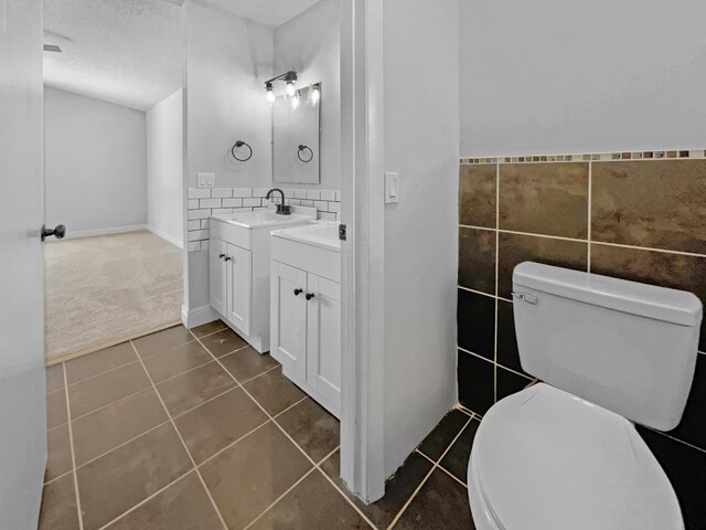 bathroom featuring tile walls, toilet, a textured ceiling, and vanity