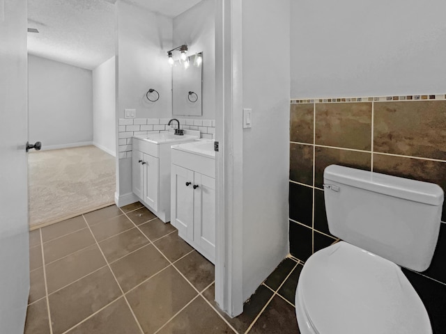 bathroom with tile patterned flooring, a wainscoted wall, toilet, vanity, and tile walls