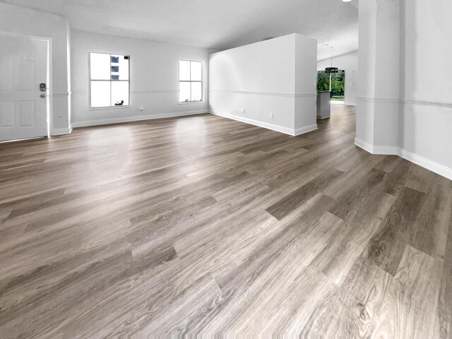 unfurnished living room with a textured ceiling and wood-type flooring