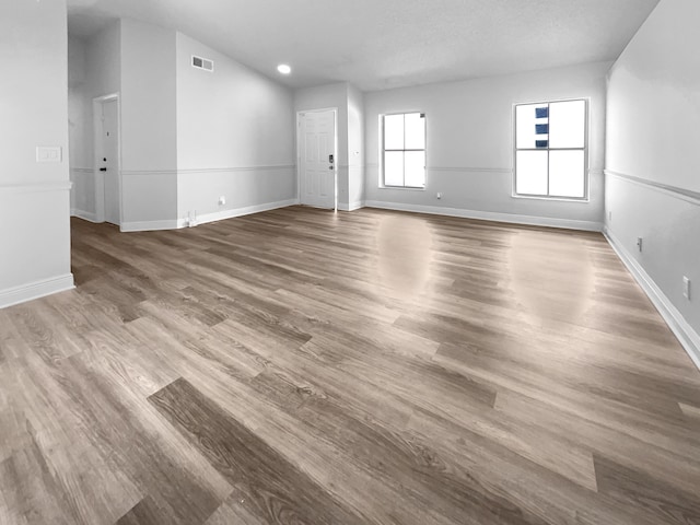 empty room with visible vents, baseboards, and wood finished floors