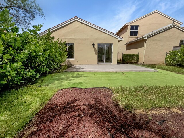 rear view of property featuring a lawn and a patio area