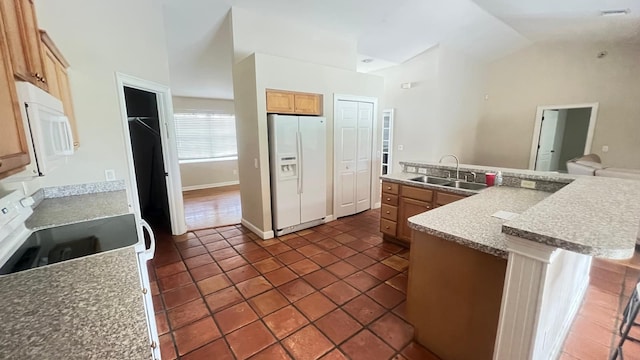 kitchen featuring white appliances, visible vents, a sink, vaulted ceiling, and dark tile patterned floors