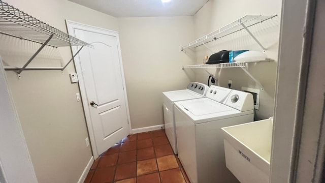 washroom with a sink, separate washer and dryer, tile patterned flooring, baseboards, and laundry area