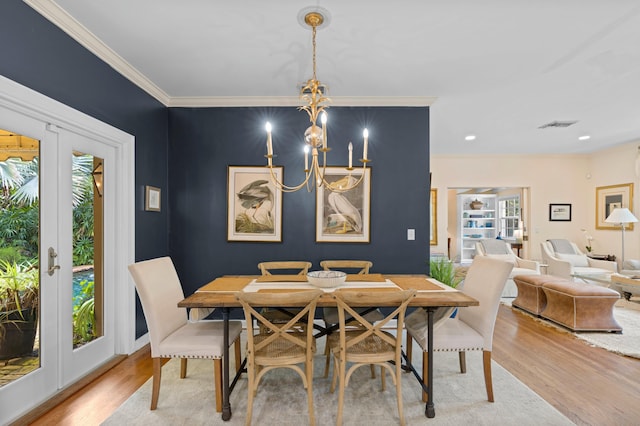 dining area featuring a healthy amount of sunlight, ornamental molding, light hardwood / wood-style flooring, and a notable chandelier