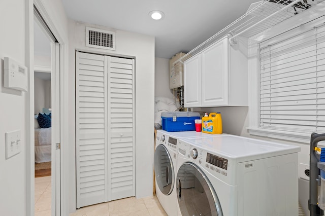 laundry area featuring cabinets, water heater, light tile patterned floors, and washing machine and dryer