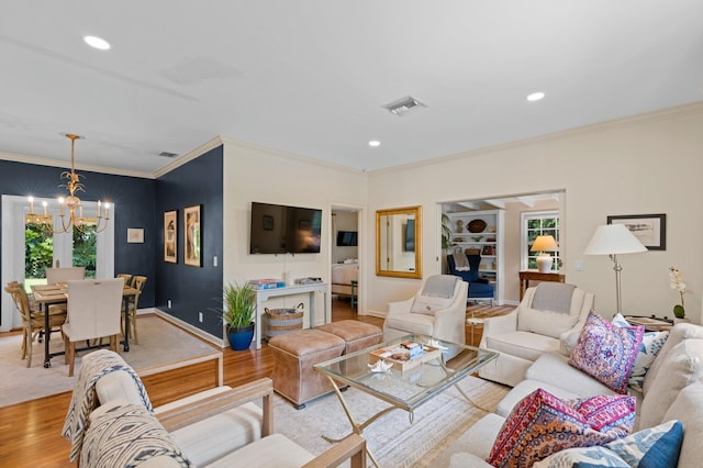 living room featuring an inviting chandelier, light hardwood / wood-style floors, and ornamental molding