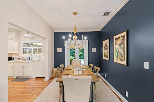 dining area with light wood-type flooring, ornamental molding, a notable chandelier, and plenty of natural light