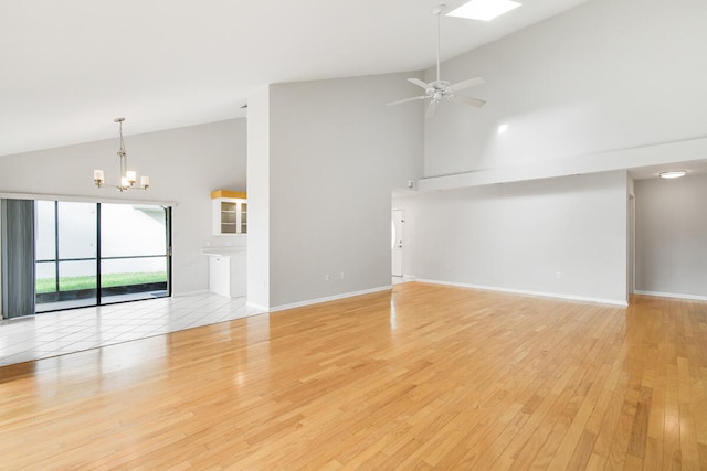 unfurnished living room with ceiling fan with notable chandelier, high vaulted ceiling, and light hardwood / wood-style flooring