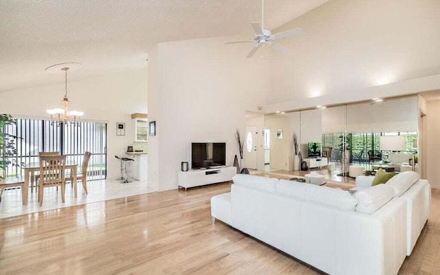 living room with ceiling fan with notable chandelier, high vaulted ceiling, light hardwood / wood-style floors, and a textured ceiling