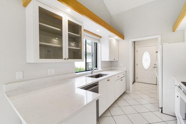 kitchen featuring vaulted ceiling, light tile patterned floors, sink, white cabinetry, and white refrigerator