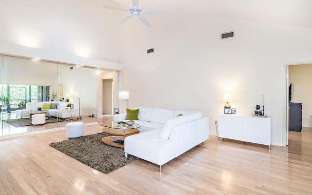 living room with ceiling fan, high vaulted ceiling, and light hardwood / wood-style flooring