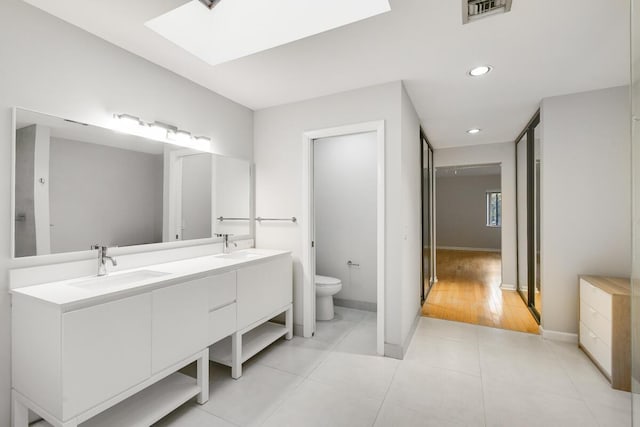 bathroom featuring vanity, a skylight, tile patterned floors, and toilet