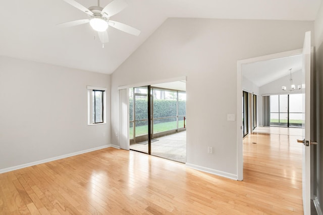 spare room with high vaulted ceiling, ceiling fan with notable chandelier, and light hardwood / wood-style floors