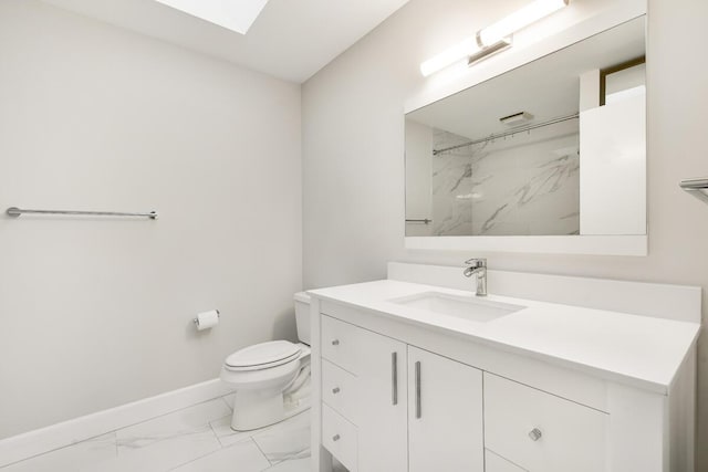 bathroom with vanity, a skylight, toilet, and tiled shower