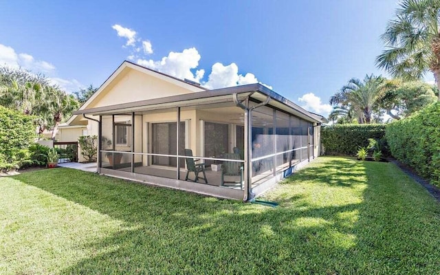 back of property with a yard and a sunroom