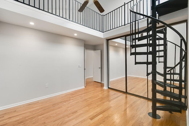 stairway with a towering ceiling, hardwood / wood-style flooring, and ceiling fan