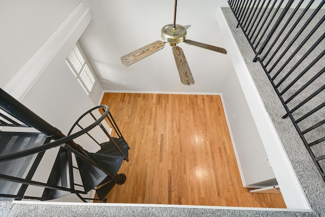 stairway featuring hardwood / wood-style floors, a high ceiling, and ceiling fan