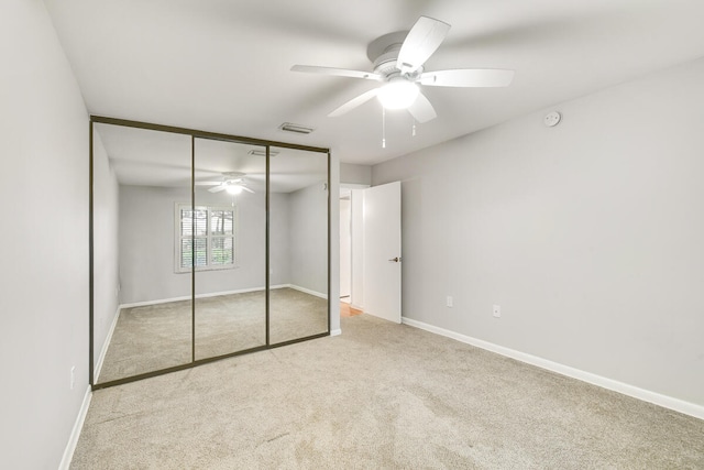 unfurnished bedroom with ceiling fan, a closet, and light carpet