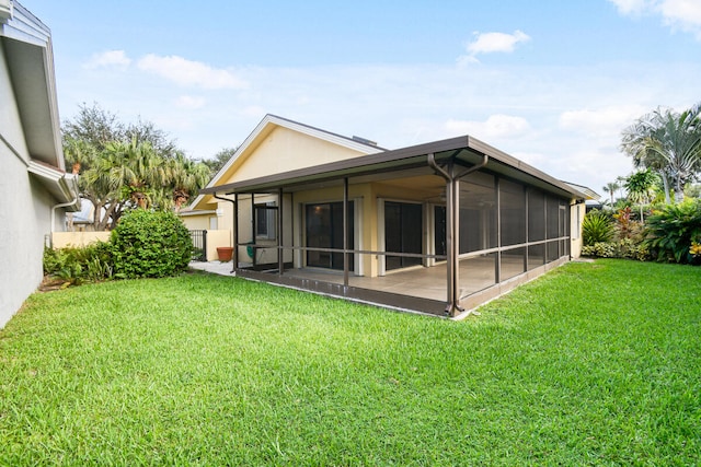 rear view of house with a lawn and a sunroom