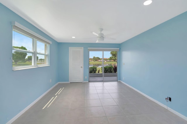 spare room with a wealth of natural light, ceiling fan, and light tile patterned flooring