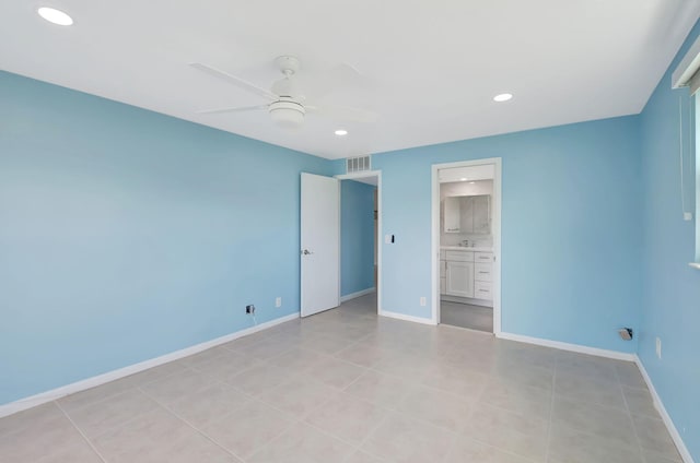 unfurnished bedroom with ensuite bath, light tile patterned floors, and ceiling fan