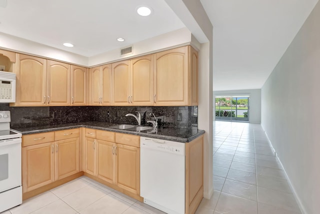 kitchen featuring white appliances, light brown cabinets, dark stone countertops, and sink