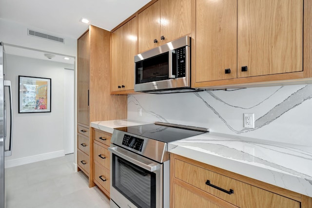 kitchen featuring appliances with stainless steel finishes, backsplash, and light stone counters