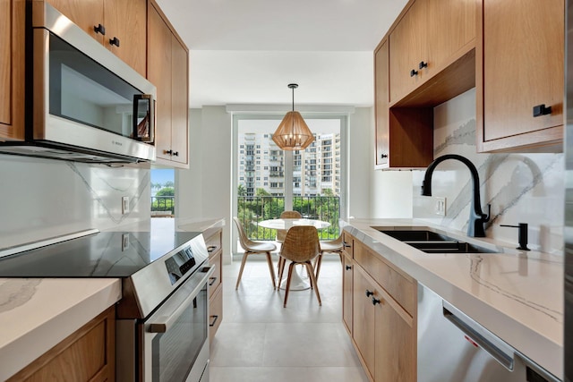 kitchen with a chandelier, sink, hanging light fixtures, decorative backsplash, and appliances with stainless steel finishes