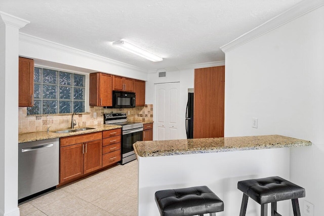 kitchen with light stone counters, a breakfast bar, kitchen peninsula, black appliances, and sink