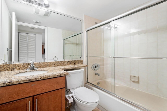 full bathroom with bath / shower combo with glass door, vanity, and toilet